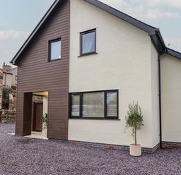 An exterior view of a house with gravel and a plant at Pistyll Ddu in Brynsiencyn near Llanfairpwllgwyngyll