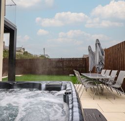 A garden with a hot tub and dining table at Pistyll Ddu in Brynsiencyn near Llanfairpwllgwyngyll