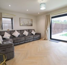 A living room with a sofa and sliding glass door at Pistyll Ddu in Brynsiencyn near Llanfairpwllgwyngyll