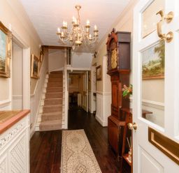 A hallway with a staircase and chandelier at Ladye Park in Liskeard