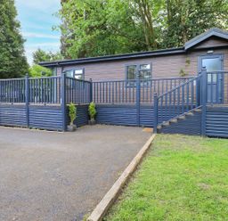 An outdoor view of a building with a deck and steps at Evermore Lodge, 48 Calgarth Park, White Cross Bay, Windermere