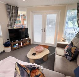 A living room with a television and a coffee table at Evermore Lodge, 48 Calgarth Park, White Cross Bay, Windermere
