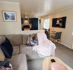 A living room with a sofa and dining area at Evermore Lodge 48 Calgarth Park, White Cross Bay, Windermere