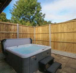 A hot tub with steps and wooden fence at Woodlands View in Leek