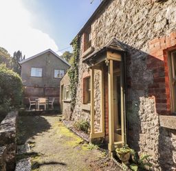 A view of a stone wall with a door and table at Rock Cottage in Milnthorpe