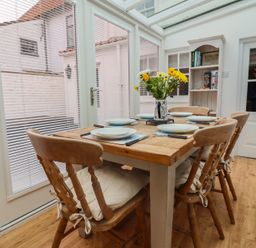 A conservatory with a table and chairs at The Nutshell in Aldeburgh