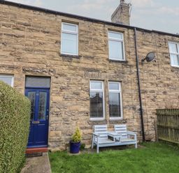 A stone exterior with a blue door and windows at 23 Northumbria Terrace Amble