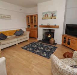 A living room with a sofa, armchair, and fireplace at 23 Northumbria Terrace Amble