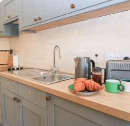 A kitchen featuring a sink, cooking hob, oven, and kitchenware at Swallow Studio in Andoversford near Cheltenham