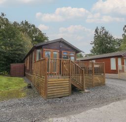 A wooden cabin with a deck and garden area at 32 Grasmere in Windermere