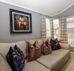 A living room with a couch and wall art at 32 Grasmere, White Cross Bay near Windermere