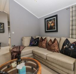 A living room with a sofa, table, and paintings at 32 Grasmere, White Cross Bay near Windermere