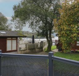 An outdoor view of boats at a dock with trees and buildings at 7 Lake View in Windermere
