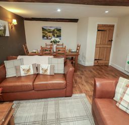 A living room with a sofa and dining area at Duchess Cottage in Woodbridge