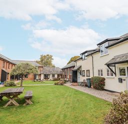 An outdoor area with buildings and a picnic bench at Rushmoor Cottage in Colaton Raleigh