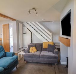 A living room with sofa and television at Rushmoor Cottage in Colaton Raleigh