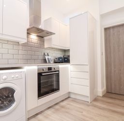 A kitchen with a washing machine and oven at Teylu in Camborne