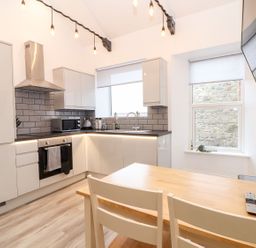 A kitchen with appliances and dining table at Battell Chambers Camborne