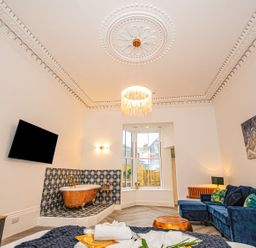 A bathroom with a bathtub and wall-mounted television at Mews Retreat in Camborne