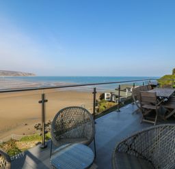 An outside area with seating and a view of the beach at Gilfach Goed in Abersoch