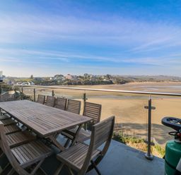 A dining area with a table and chairs on a balcony at Gilfach Goed in Abersoch