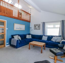 A living room with a blue sofa and wooden coffee table at Gilfach Goed in Abersoch