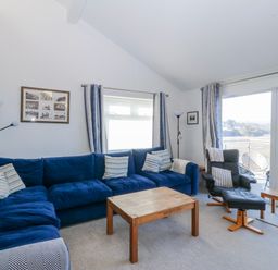 A living room with a blue sofa and coffee table at Gilfach Goed in Abersoch