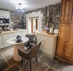 A kitchen with stone walls and wooden cabinets at Gwyn Studio in Aberdare