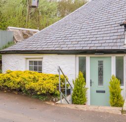 An entrance with a green door and shrubs at Round Barn in Ilfracombe
