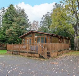 A wooden cabin with a deck in an outdoor area at 5 Waterside Wood Troutbeck Bridge