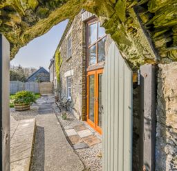 An outdoor pathway with a stone wall and door at The Old Farm House near Pelynt