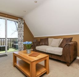 A living room with a sofa, coffee table, and glass door at Valley Lodge 61 Callington
