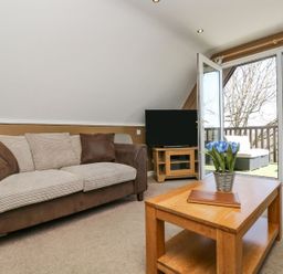 A living room with a sofa, coffee table, and television at Valley Lodge 61 in Callington