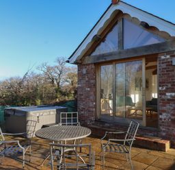 An outdoor patio with a table and chairs at Hilldown Cott near Bow