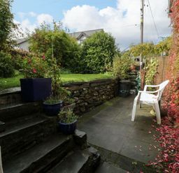 A garden with a stone wall and chair at Noddfa in Penmachno