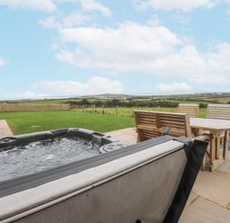 An outdoor area with a hot tub and seating at 2 Trem Y Mor Llanfwrog near Llanfachraeth