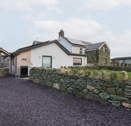 An exterior view of a house and stone wall at Hen Penmynydd Llanfwrog near Llanfachraeth