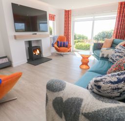 A living room with a fireplace and a television at Shearwater in Praa Sands