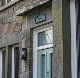 An entrance with a green door and stone wall at Green Bank in Betws-Y-Coed