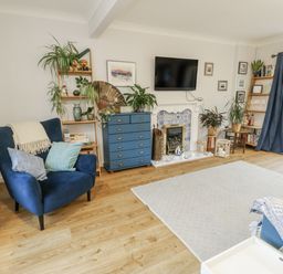 A living room with a television and blue armchair at 16 Ffordd Meigan in Beaumaris