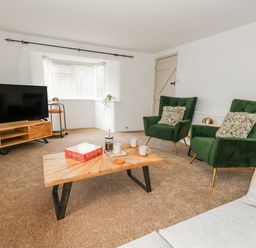 A living room with green armchairs and a coffee table at Long Barn in Burton Bradstock