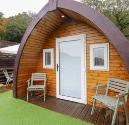 An outdoor area with wooden pod structure and seating at Cwtch Bach Aberdare