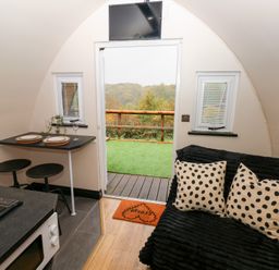 An interior view with table, sofa and kitchen area at Cwtch Bach in Aberdare