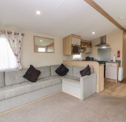 A living room with a sofa and kitchen area at Peaceful in Stranraer