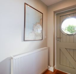 A hallway featuring a map on the wall and a round door at The Mizzen St Endellion near Port Isaac