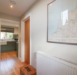 A hallway with a map on the wall and a view of the kitchen at The Mizzen in St Endellion near Port Isaac