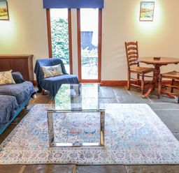 A living room with a sofa, coffee table, and dining set at Owl Cottage, Kettleburgh near Framlingham