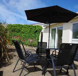 An outdoor seating area with a table and chairs at Badgers Cliff in Polzeath