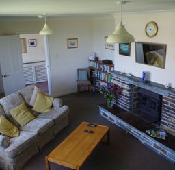 A living room with a sofa and fireplace at Badgers Cliff in Polzeath