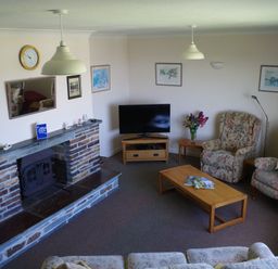 A living room with a television and fireplace at Badgers Cliff in Polzeath